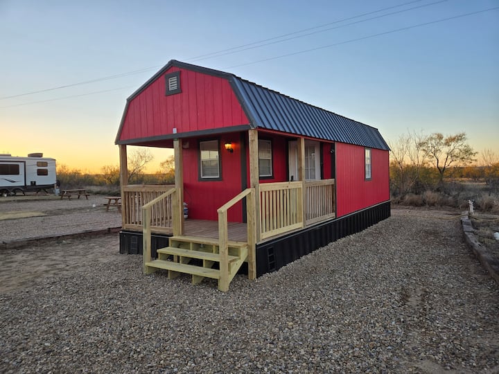 The red rental cabin and its covered porch at Camp Meredithville